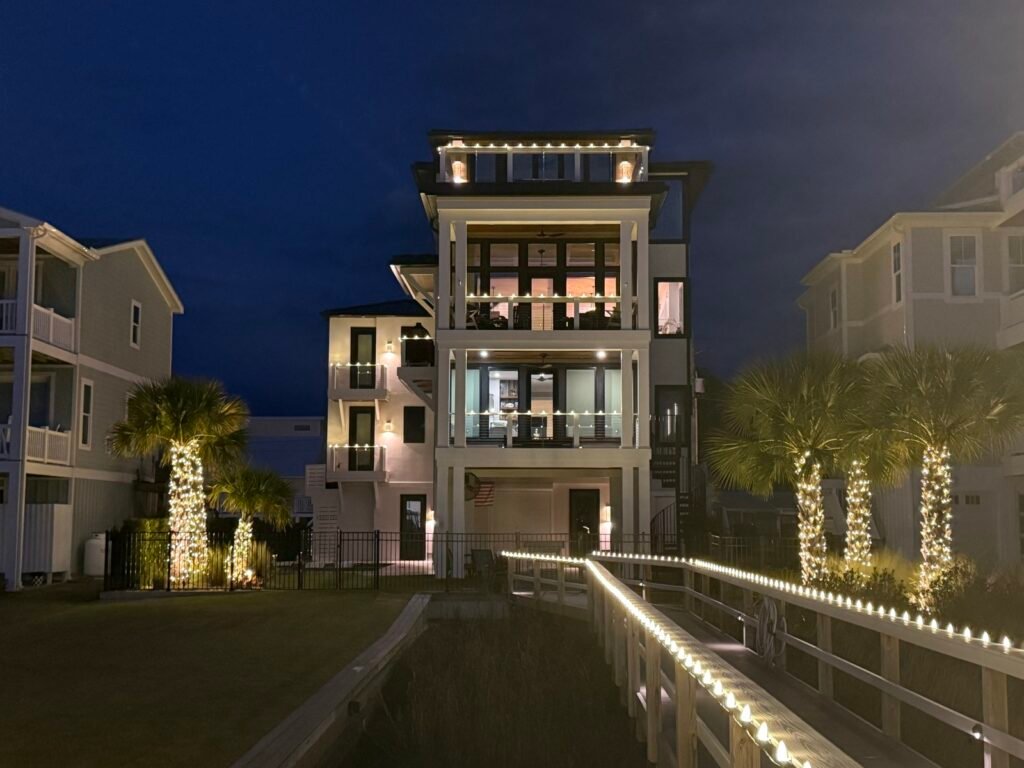 Christmas lights on a tall coastal home with palm trees by Shark Illumination