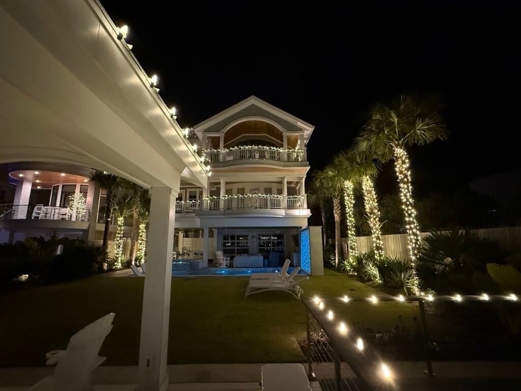 Christmas lights on a waterfront home with lit palm trees by Shark Illumination